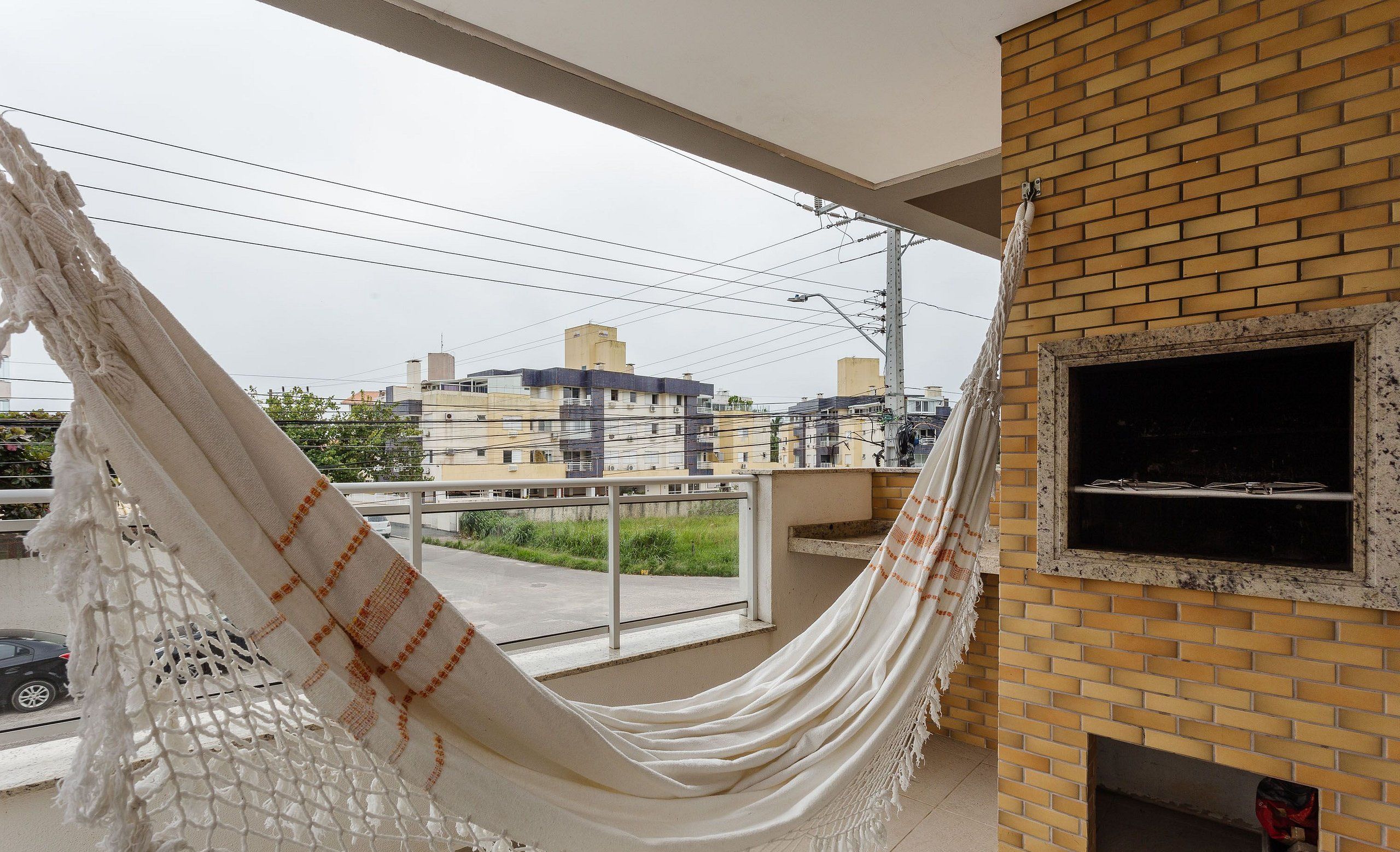 Una hamaca en un balcón con un muro de ladrillo y una chimenea.