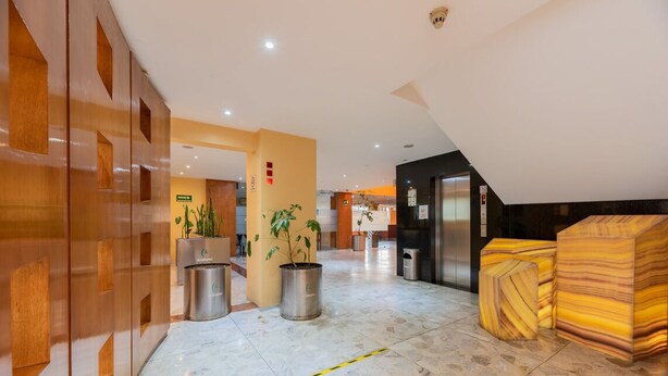 A hotel lobby with a modern design, featuring a marble floor, wooden accents, and potted plants. - Hotel Ecatepec (Ecatepec de Morelos)