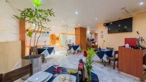 A restaurant with tables set for dining, a reception desk, and a large screen on the wall. - Hotel Ecatepec (Ecatepec de Morelos)