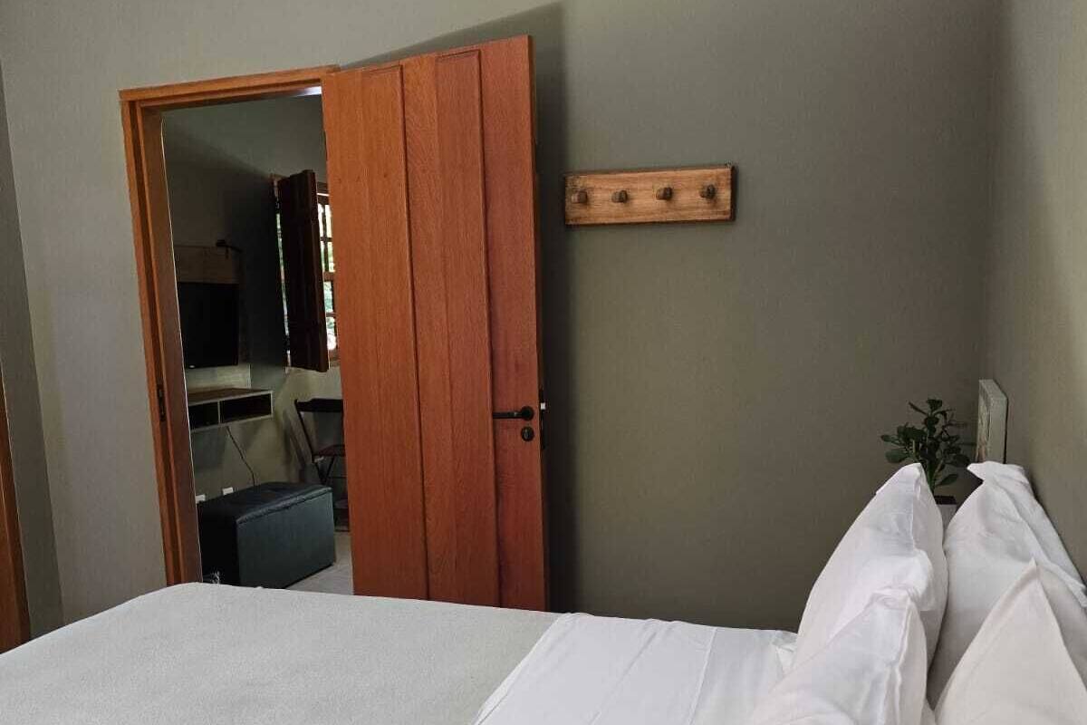 A bedroom with a bed, a wooden door, and a small plant.