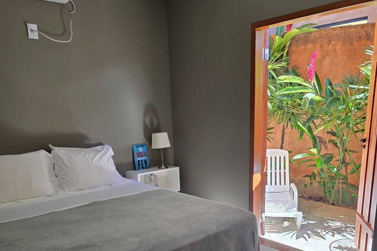 A bedroom with a bed, bedside table, lamp, and a view of a garden through a sliding door.