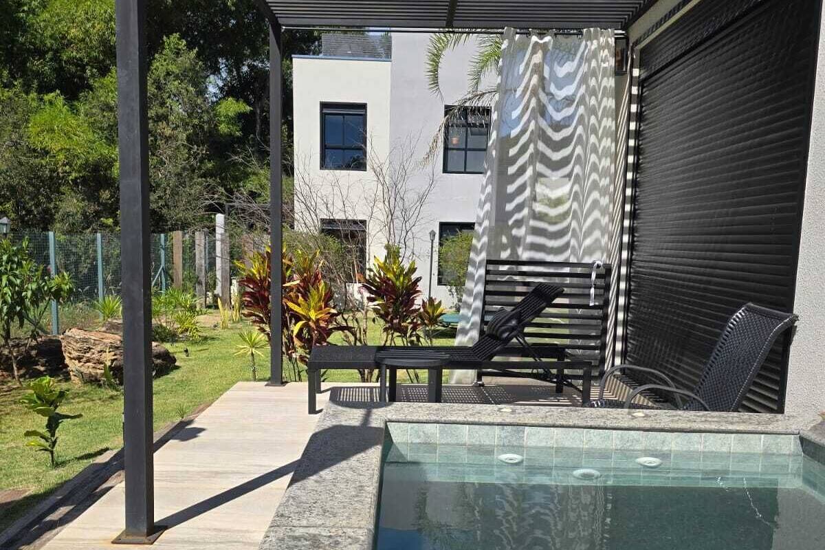 A modern outdoor pool area with a covered seating area and a view of a white building in the background.