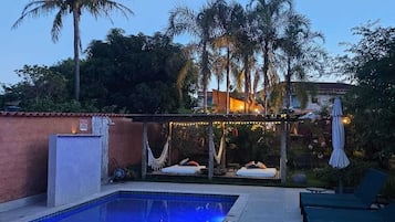 Una piscina al aire libre, sillones reclinables de piscina