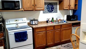 A kitchen with wooden cabinets, a stove, a microwave, and a sink. - Stylish, Modern & Cozy Garden Apartment near Chicago (Beecher)