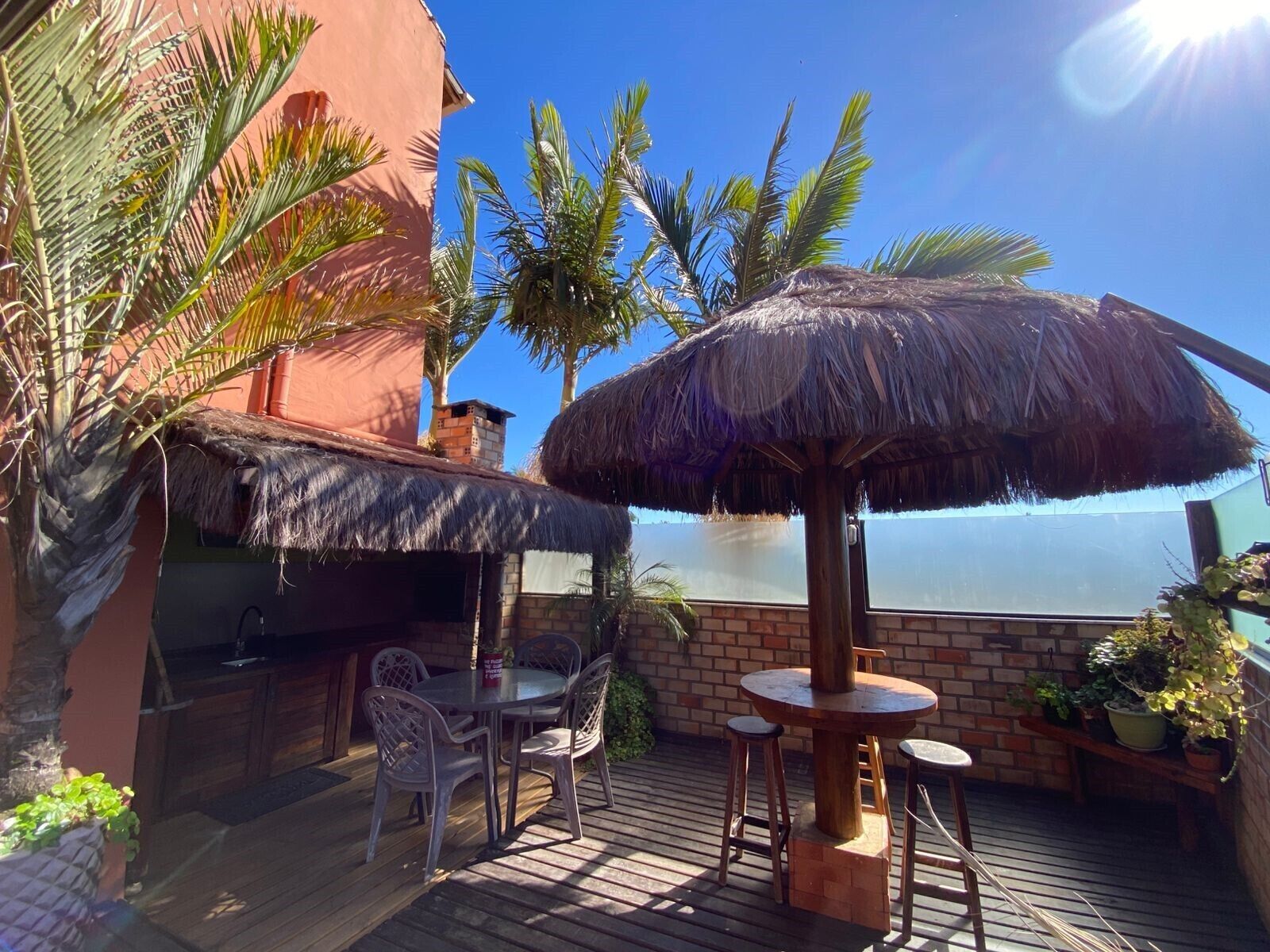 Une terrasse extérieure avec une table ronde, des chaises et un parasol en chaume.