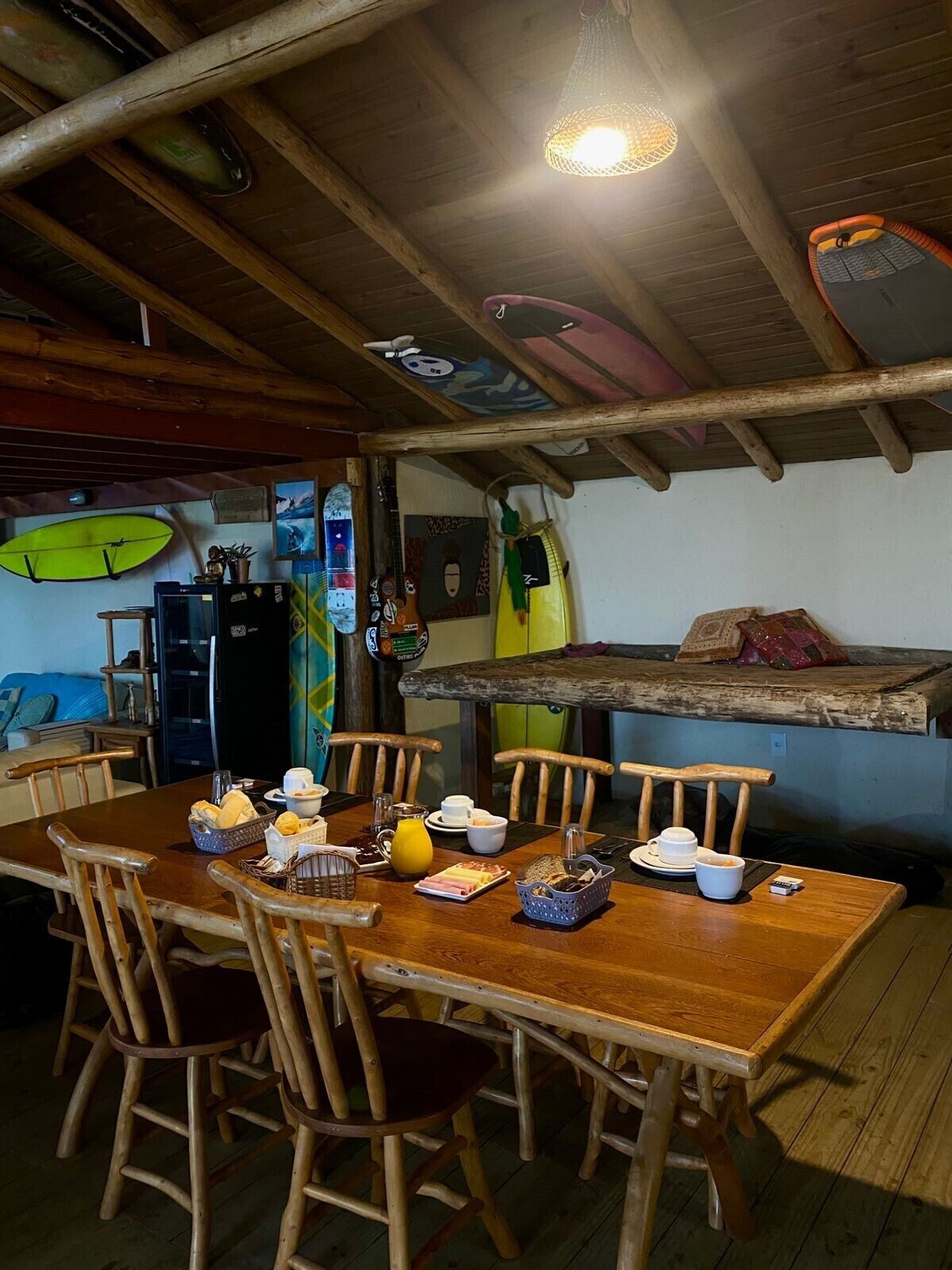 Ein rustikaler Essbereich mit Holzkästen, Holzbalkendecke und Surfbrettern an der Wand.