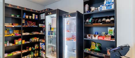 A self-service kiosk area with refrigerated display cases and shelves stocked with various food items and beverages.