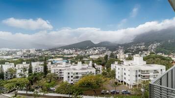 A residential area with modern buildings, a clear sky, and a mountain in the background.