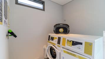 A laundry area with a washing machine and dryer, a small window, and a wall-mounted security camera.