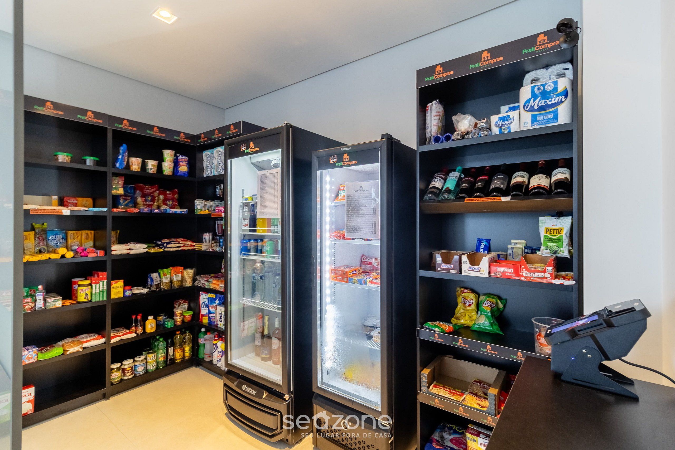 Zona de quioscos de autoservicio con vitrinas refrigeradas y estantes llenos de diversos alimentos y bebidas.