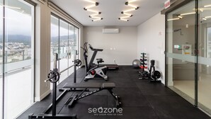 Ein modernes Fitnessstudio mit Trainingsgeräten, großen Fenstern und Blick auf die Stadt.