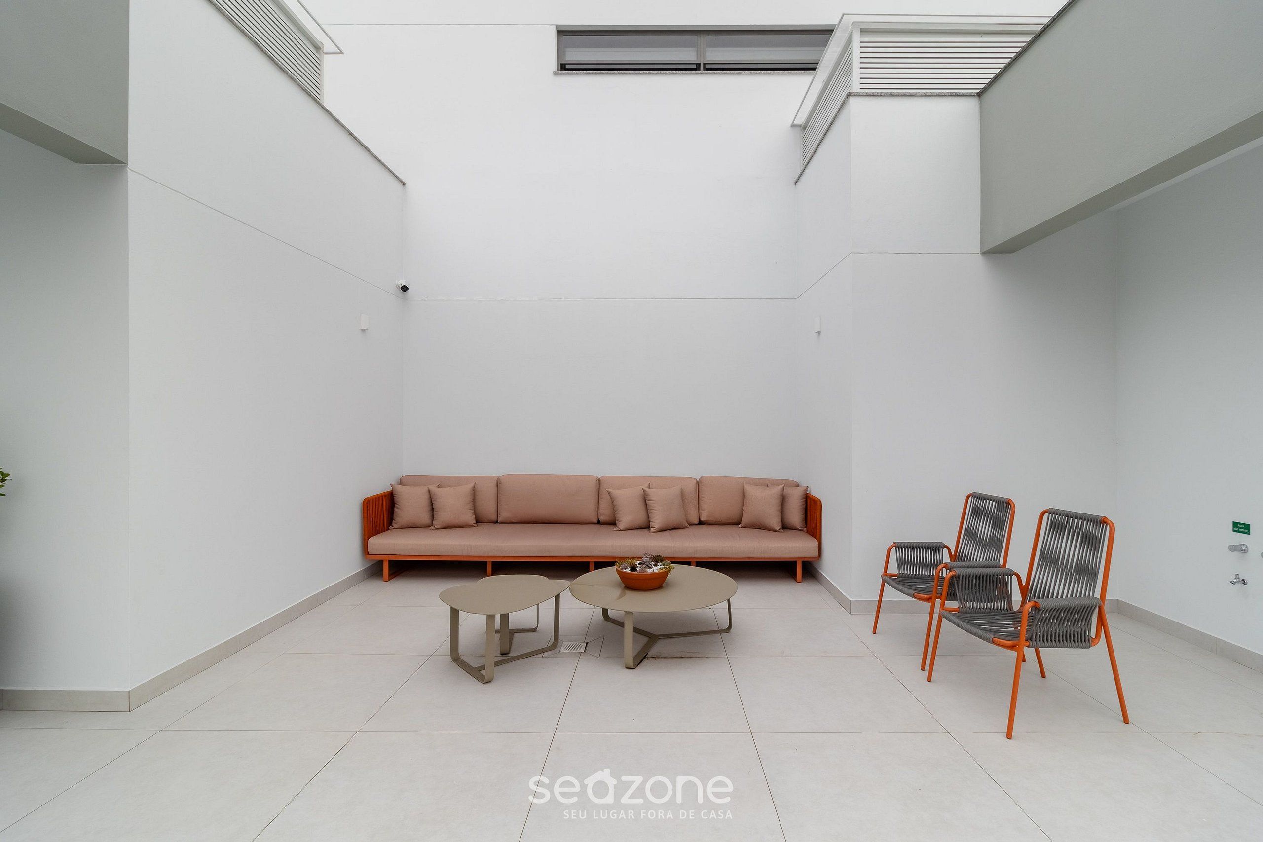 Un espacio habitable moderno y minimalista con un sofá, dos mesas pequeñas y tres sillas.