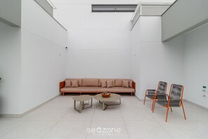 Un espace de vie moderne et minimaliste, comprenant un canapé, deux petites tables et trois chaises.