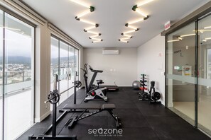 A modern gym with exercise equipment, large windows, and a city view. - Apartments Just a few Minutes From Ufsc, Condo With Laundry Facilities (Florianópolis)
