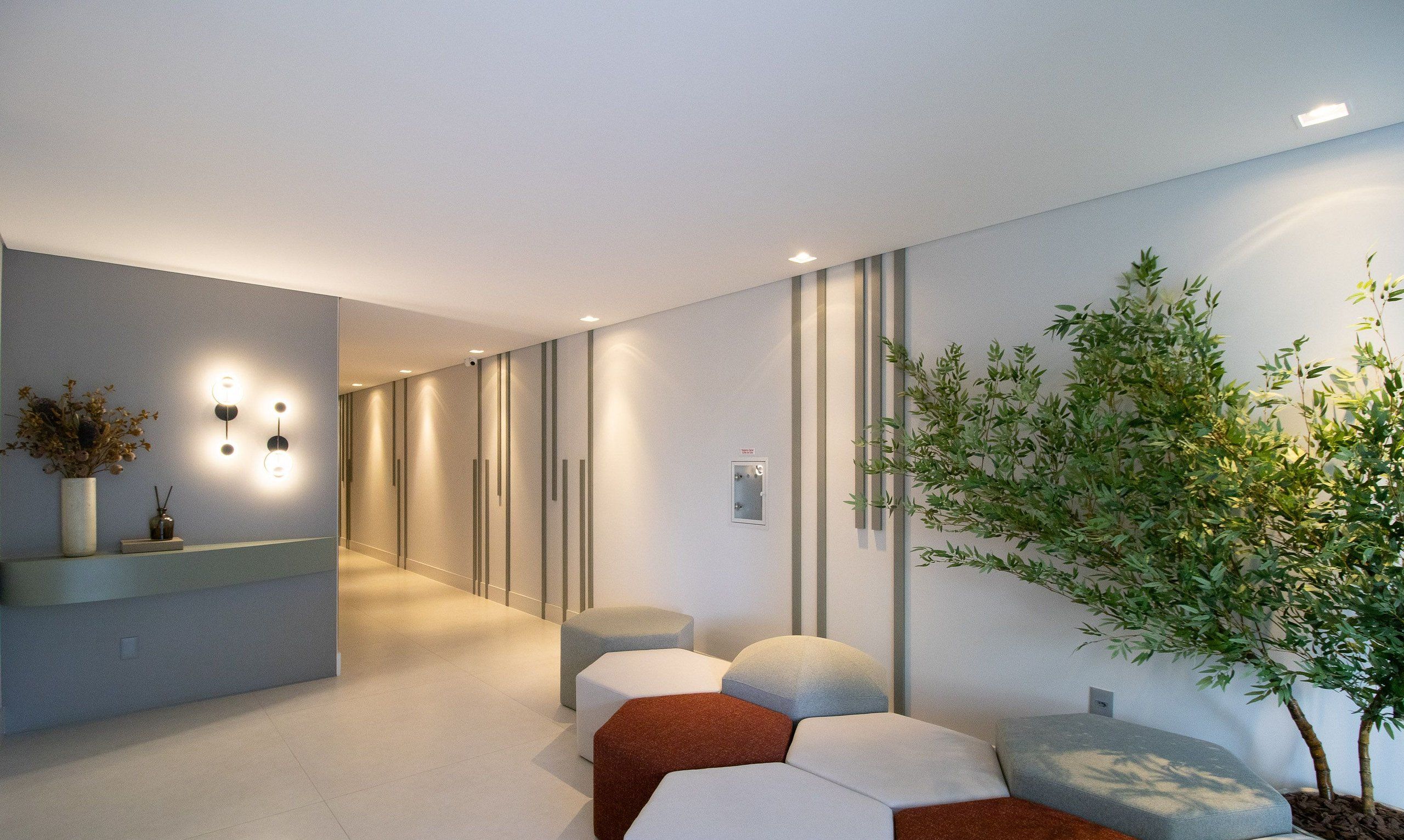 Un interior moderno con un mostrador de recepción, zona de estar y una planta.