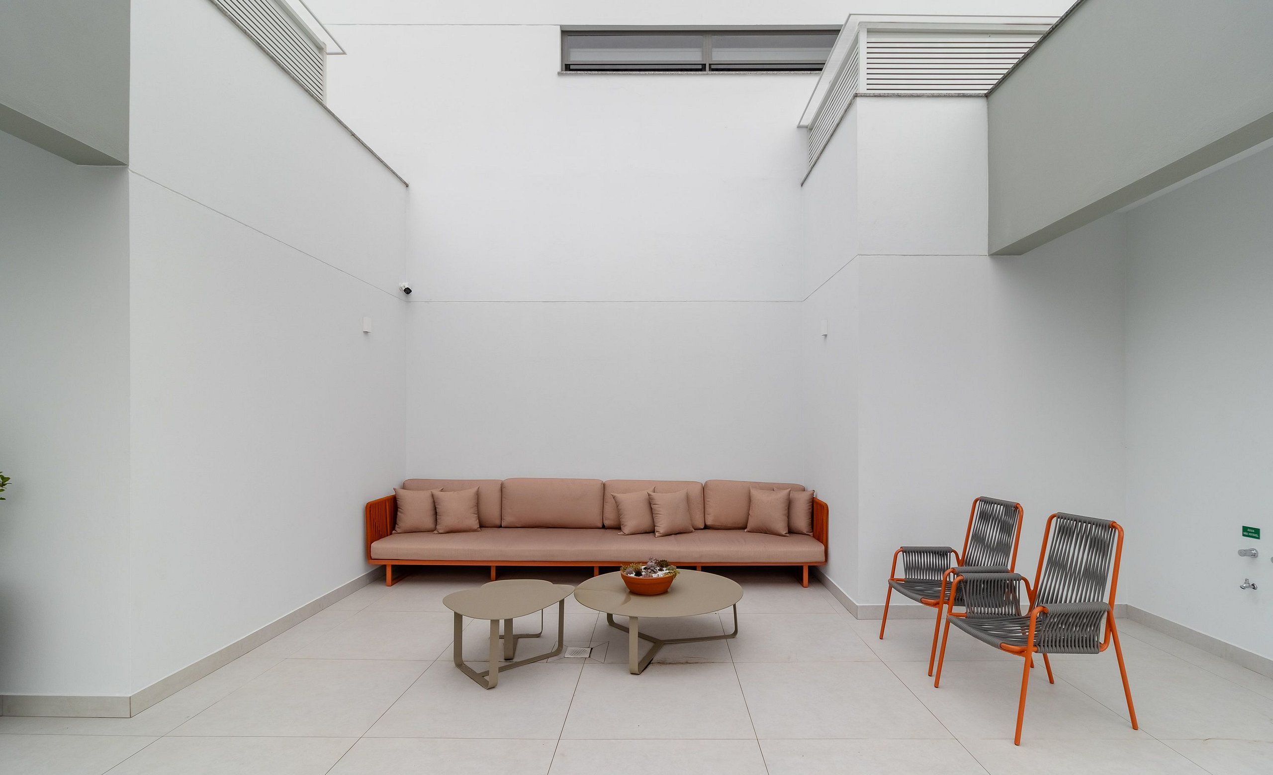 Ein moderner, minimalistischer Wohnbereich mit einer Couch, zwei kleinen Tischen und drei Stühlen.