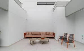 A modern, minimalist living area with a sofa, two small tables, and three chairs. - Apartments Just a few Minutes From Ufsc, Condo With Laundry Facilities (Florianópolis)