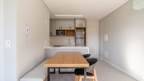 Une cuisine moderne avec une table et des chaises en bois, un four à micro-ondes et un réfrigérateur.