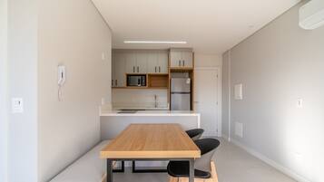 A modern kitchen with a wooden table and chairs, a microwave, and a refrigerator.
