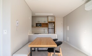 Une cuisine moderne avec une table et des chaises en bois, un four à micro-ondes et un réfrigérateur.