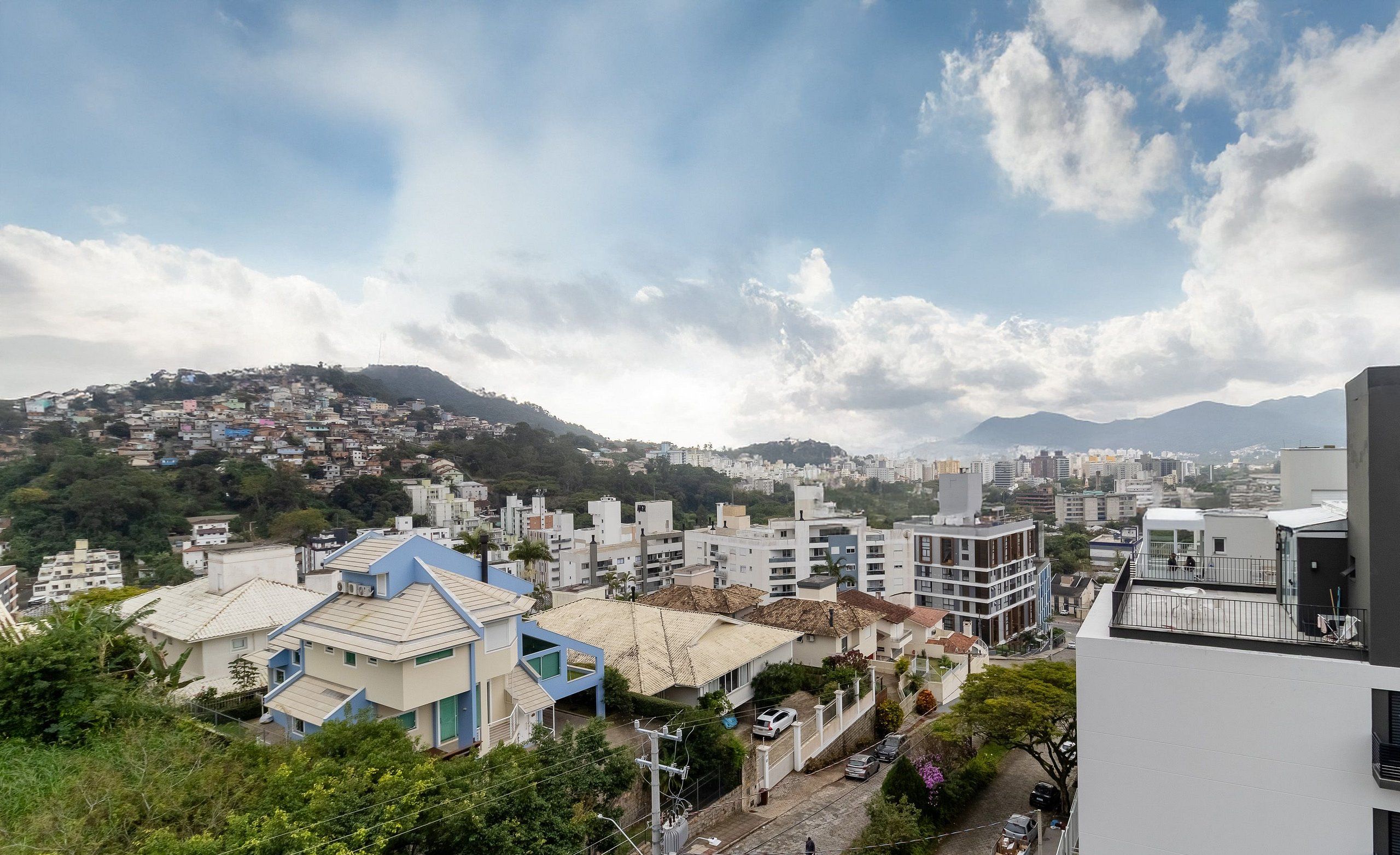 A residential area with modern buildings, a street, and a hilly background.