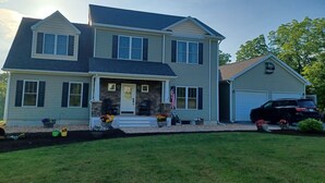 A two-story house with a front porch, a garage, and a driveway.