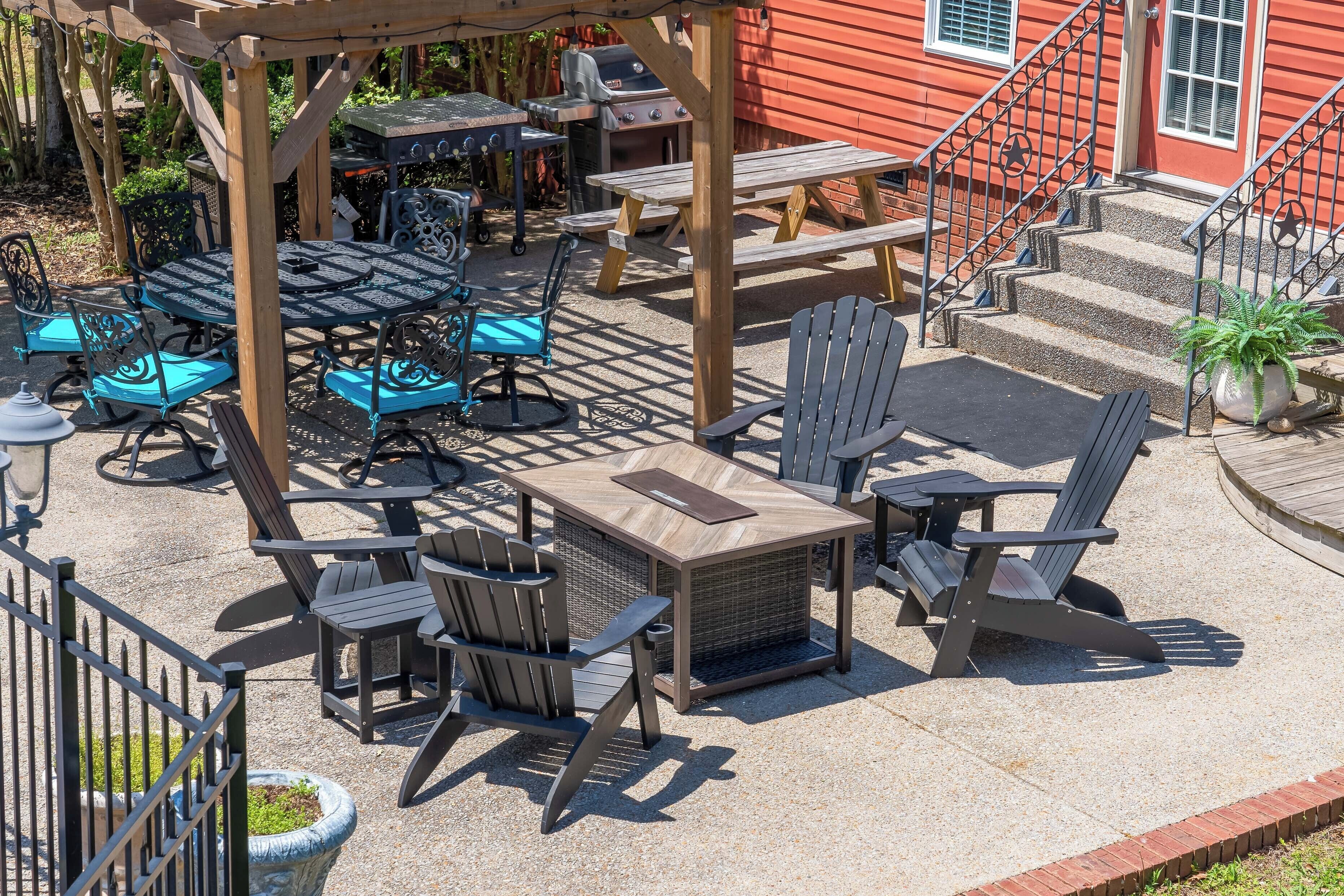 An outdoor patio with a pergola, tables, chairs, and a barbecue area.