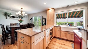 Cocina con armarios de madera, encimera de mármol y ventana con vistas al verdor.