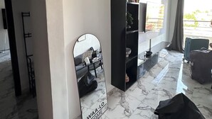 A modern living room with a marble floor, a black entertainment unit, and a large mirror with 'WAA-LO HOME' text.