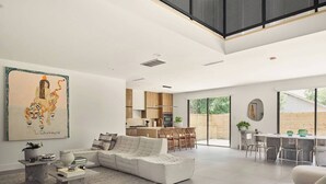 Un salón amplio con un sofá blanco, una mesa de comedor y una cocina al fondo.