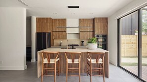 Una cocina moderna con armarios de madera, una isla central con taburetes altos y un amplio ventanal con vistas al exterior.
