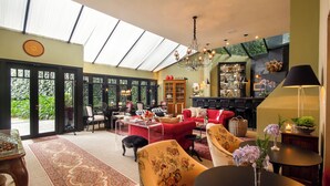 A spacious living area with a high ceiling, large windows, and a variety of seating options including sofas and armchairs. - Hotel Boutique Casa Regaleira (Campos do Jordão)