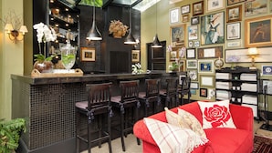 A bar area with a black tiled backsplash, multiple bar stools, and a red sofa with a white rose pillow. - Hotel Boutique Casa Regaleira (Campos do Jordão)