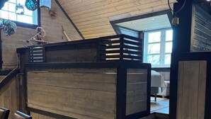 Un intérieur en bois avec un escalier, un coin repas avec des chaises et un luminaire suspendu.
