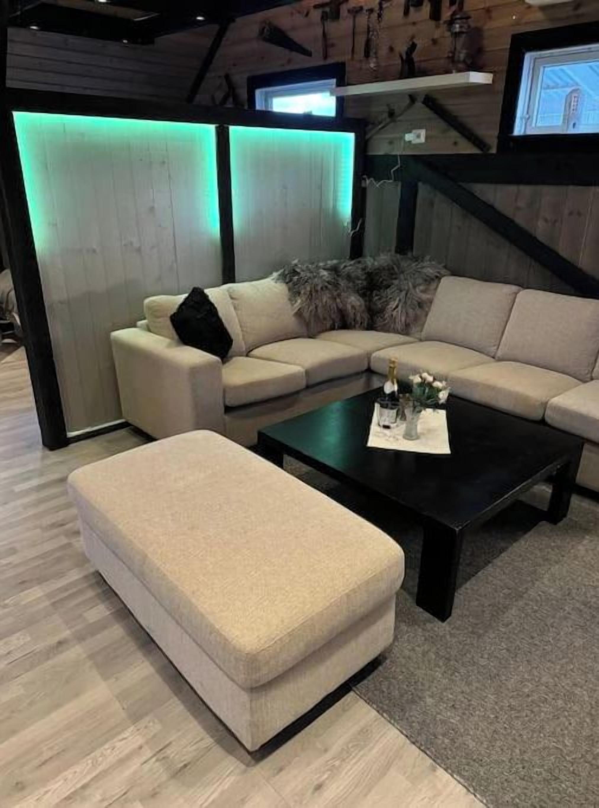 A modern living room with a sectional sofa, a coffee table, and a TV mounted on the wall.