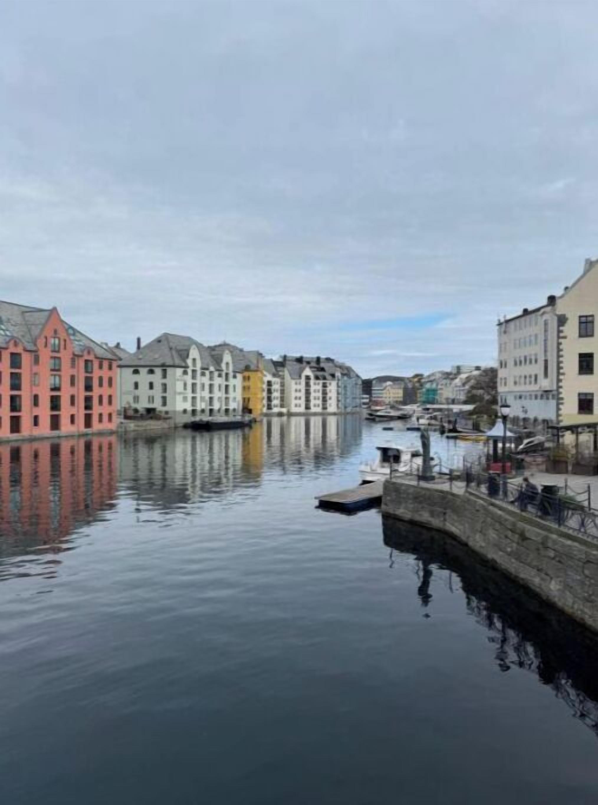 A canal with buildings on either side, including a pink building and a white building with a grey roof.