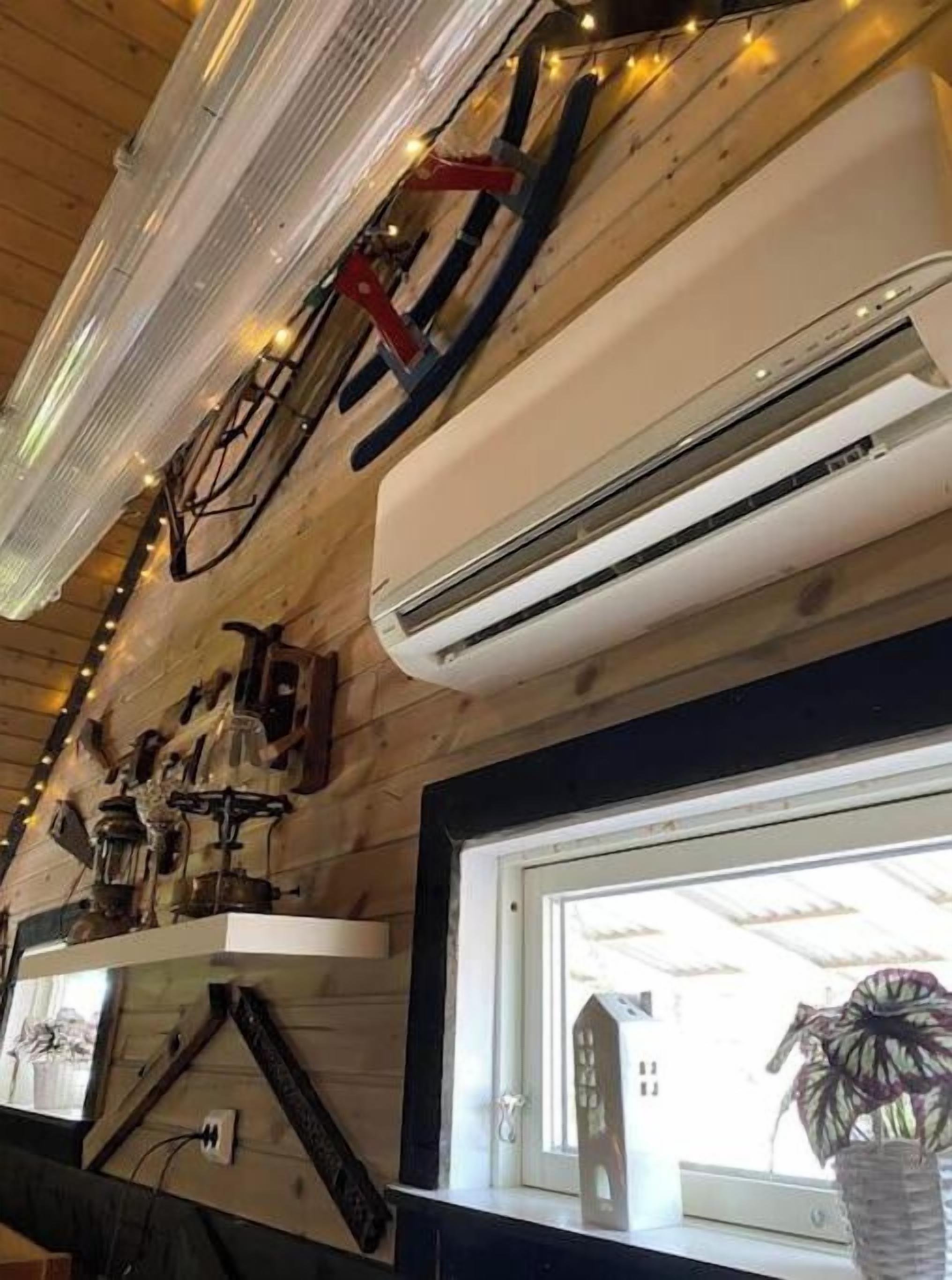 Ein Zimmer mit Holzwänden, einer Wandmontage-Klimaanlage und einem Fenster mit Blick auf ein Gebäude.