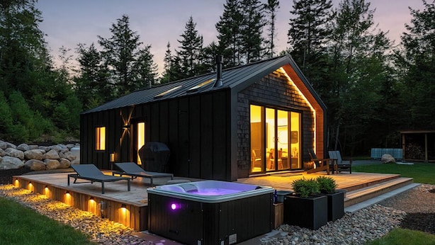 A modern cabin with a hot tub, deck, and outdoor seating area surrounded by a natural landscape. - Nalu Retreat Lakeside (Porters Lake)