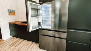 A modern kitchen with a stainless steel refrigerator, wooden countertop, and white tiled backsplash. - Nalu Retreat Lakeside (Porters Lake)