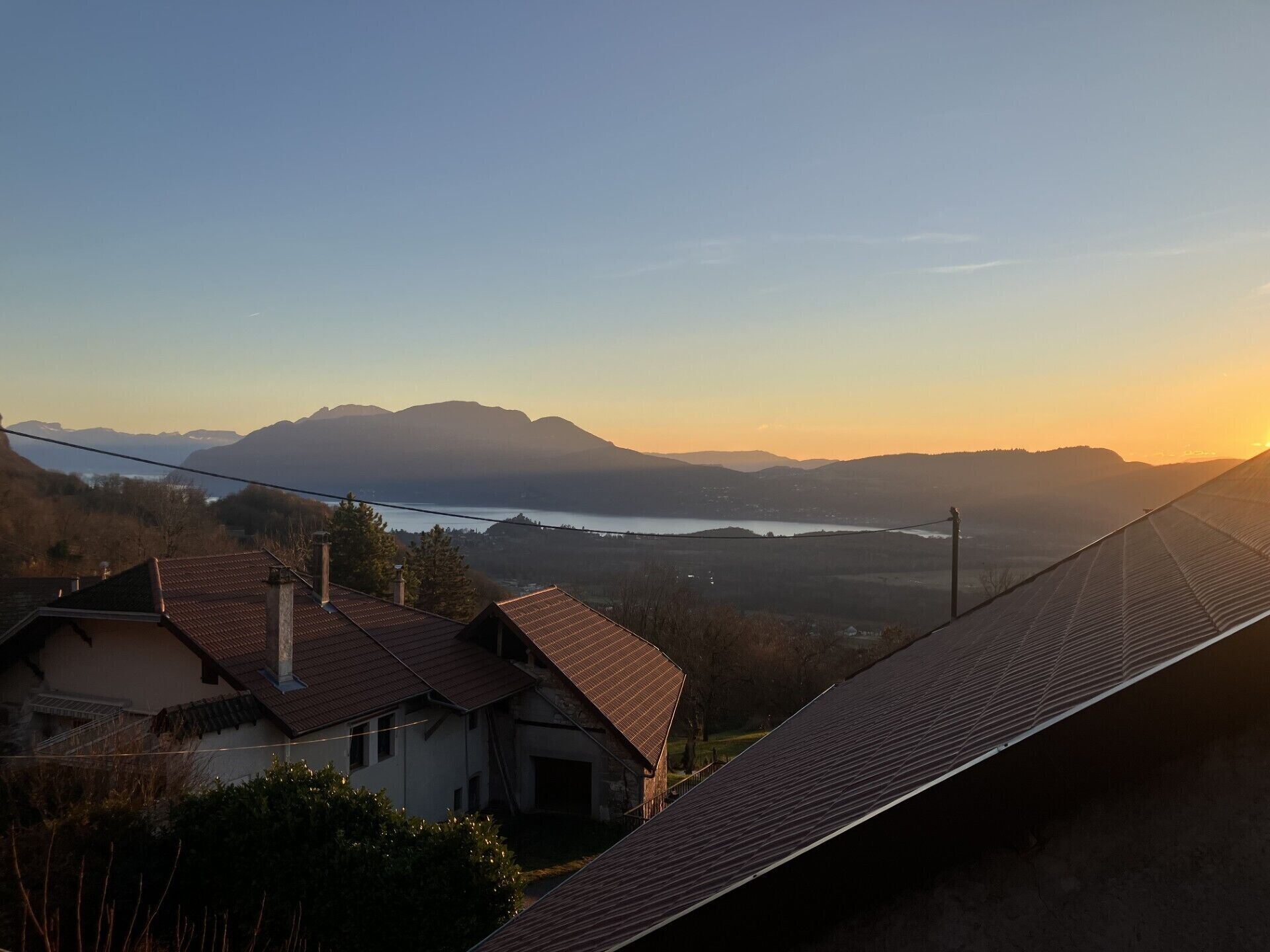 Un quartier résidentiel avec des maisons, un plan d’eau et des montagnes en arrière-plan.