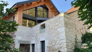 Une maison moderne avec une façade en pierre et un étage supérieur en bois.