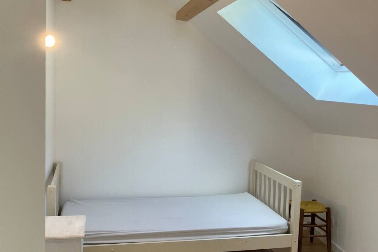 A small, single-bed room with a slanted ceiling and a skylight.