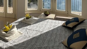 A bedroom with a large bed, a small table with a flower vase, and a view of the sea through large windows. - The Villino ai Tre Ponti (Sanremo)