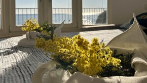 A room with a large window, a bed with a patterned bedspread, and a white decorative pillow. - The Villino ai Tre Ponti (Sanremo)