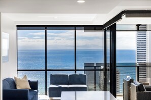 Una habitación moderna con un ventanal grande, un sofá, una mesa y vistas al océano.
