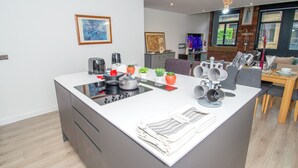 A modern kitchen with an island, built-in appliances, and a dining area with a wooden table and chairs.