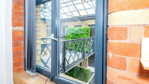 A window with a metal frame and a view of a brick wall and greenery outside.