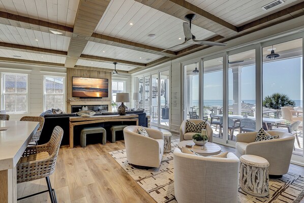 A spacious living area with a large window overlooking a cityscape, a wooden ceiling, and a modern kitchen with a large island.