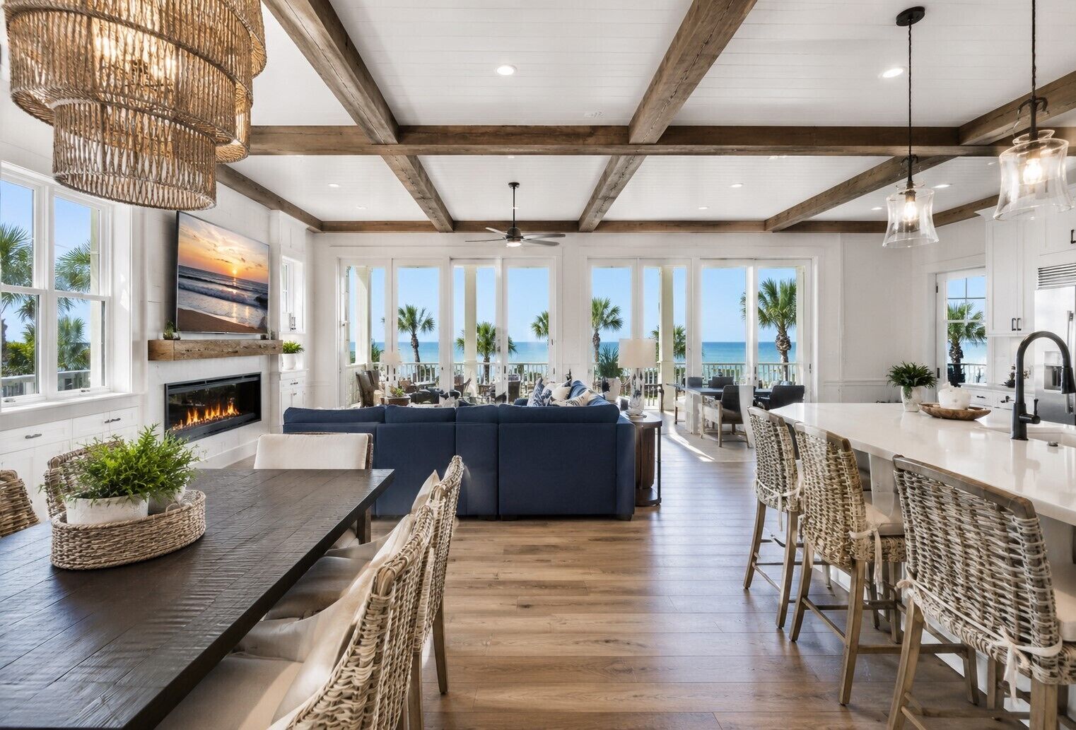 A spacious living area with a large sofa, dining table, and chairs, a fireplace, and a view of the ocean.