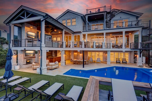 A large, multi-story house with a swimming pool, outdoor seating, and a fireplace.